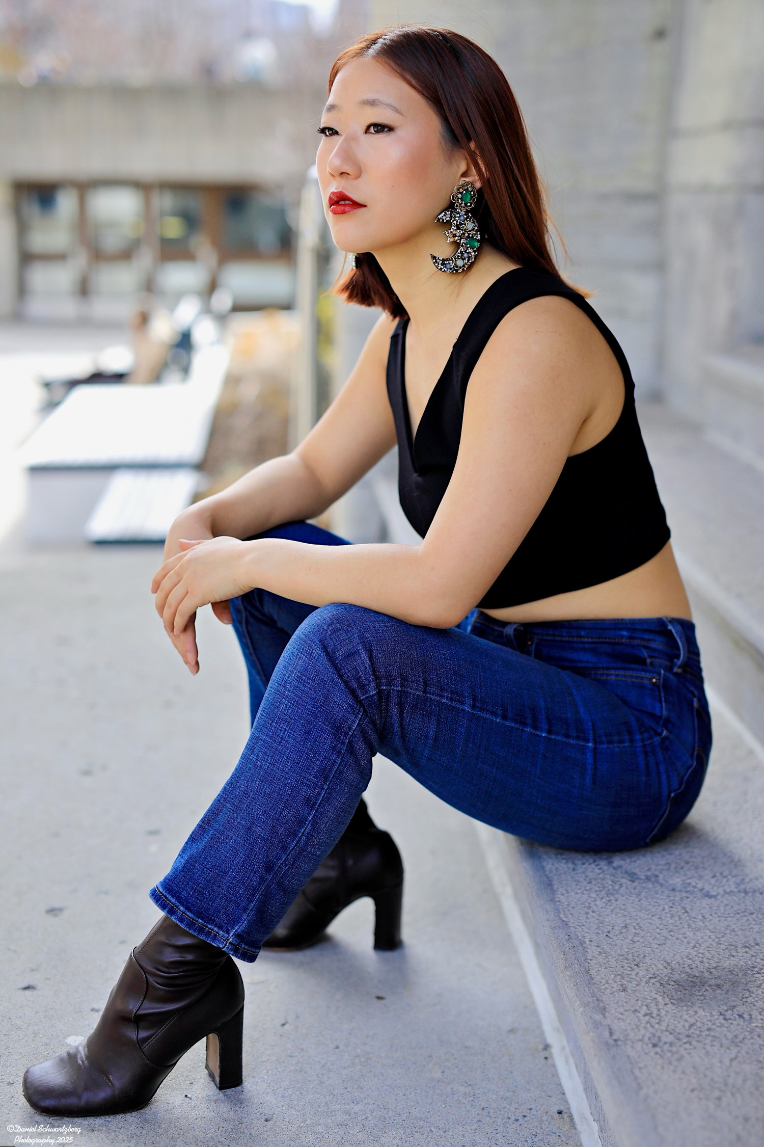 Handmade luxury statement earring featuring intricate green and silver hand-beaded detailing. A model wears the large, lightweight crescent-shaped artisan earring in a lifestyle close-up, showcasing its scale and high-end craftsmanship.