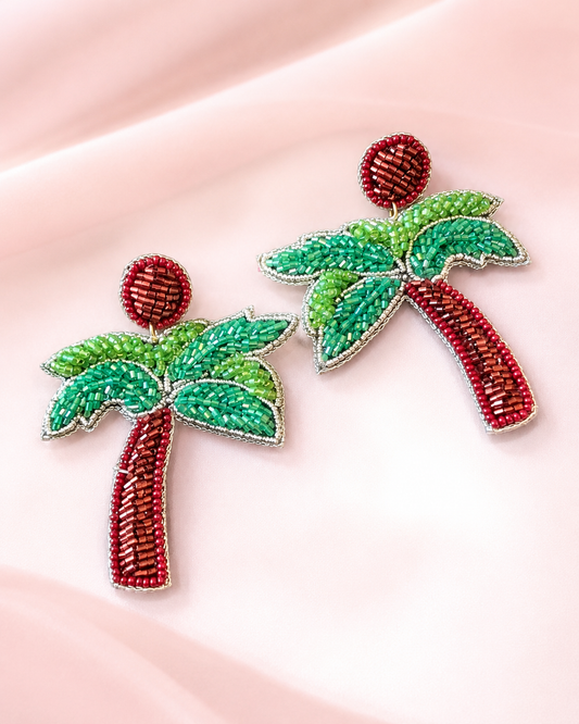 Boucles d'oreilles pendantes faites main en perles, motif palmier tropical — Handmade red and green beaded palm tree statement earrings by ZOHRICANADA on a pink background — Zohricanada