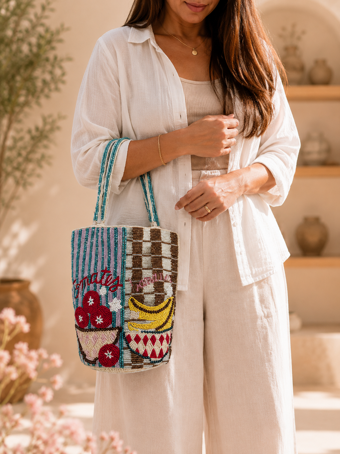 Sac cabas perlé « Marché aux fruits » | Sac à bandoulière de luxe fait main inspiré des courses — Woman in a linen outfit carrying a handmade beaded fruit market tote bag by ZOHRICANADA with tomato and banana embroidery — Zohricanada