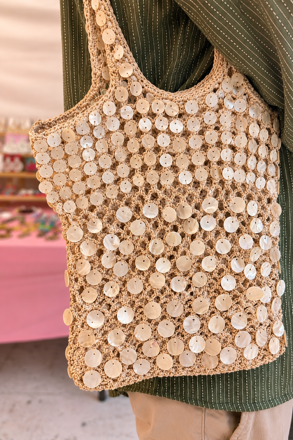 Sac fourre-tout en crochet fait main orné de coquillages | Sac de plage et de vacances | Sac fourre-tout en crochet perlé — Close-up of handmade beaded pearl shell crochet tote bag by ZOHRICANADA carried over the shoulder at an outdoor market — Zohricanada
