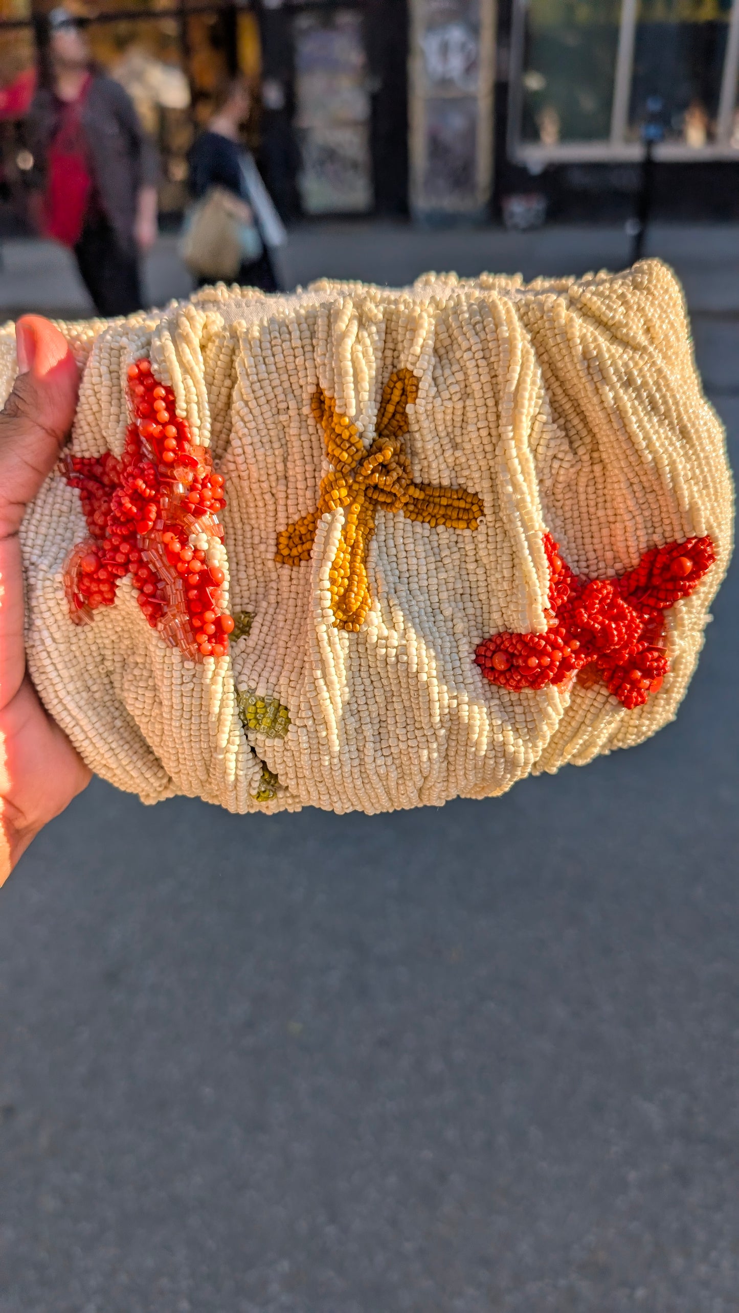 Star fish beaded bag — Beaded clutch with starfish and butterfly designs held by a hand against an outdoor background. — Zohricanada